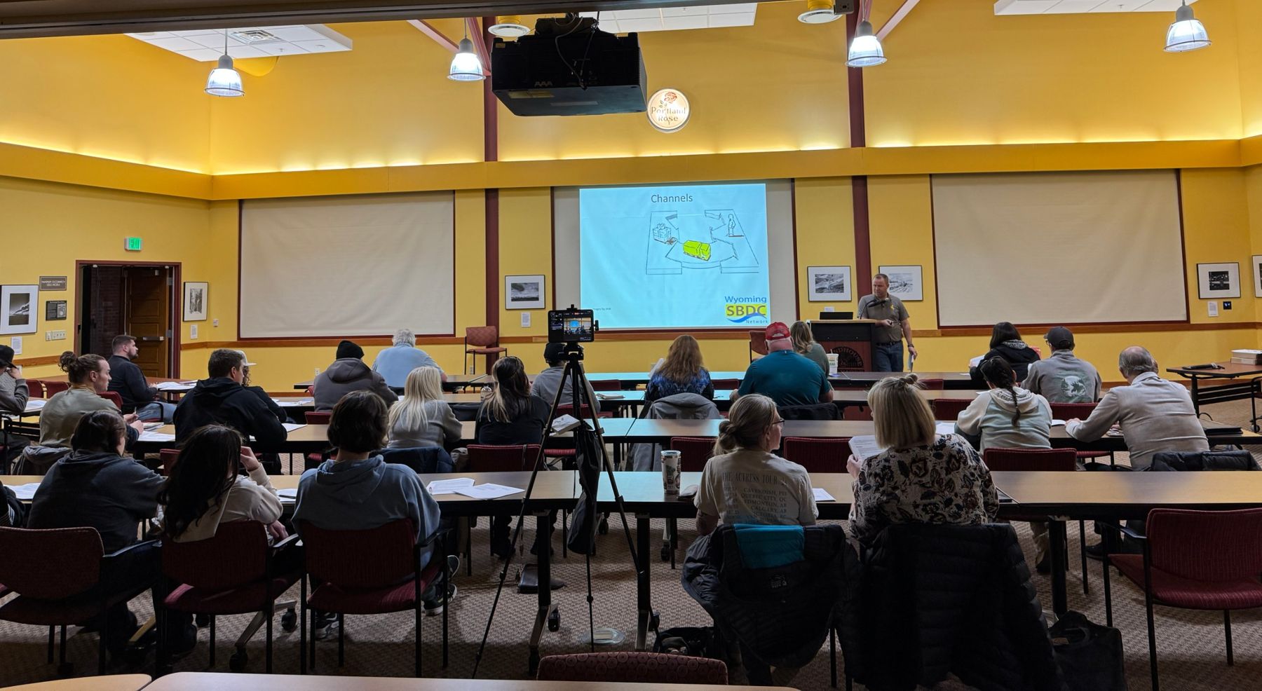 A full room of Jumpstart participants at tables listening to a Wyoming SBDC Network presentation on business model channels